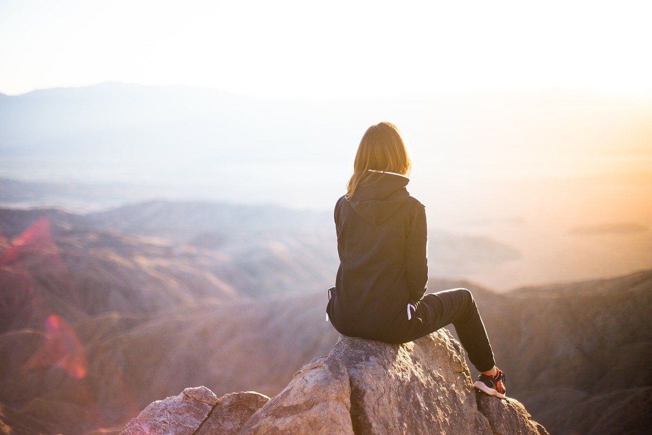 Frau sitzt auf Gipfel schöner Ausblick Wanderbekleidung Tipps zur Auswahl