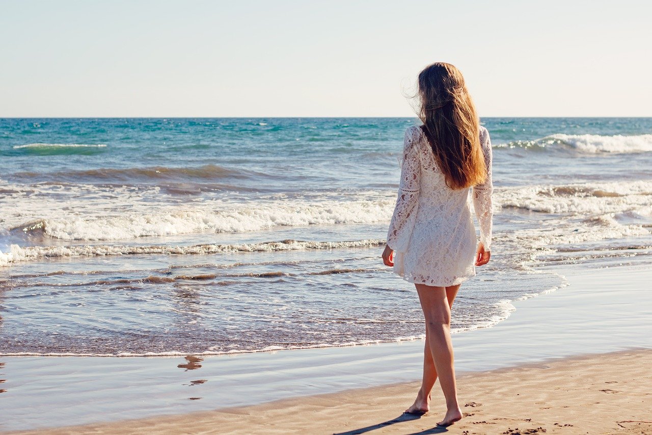 junge Frau am Strand im Sommerurlaub Praktische Accessoires für Ihren Sommerurlaub